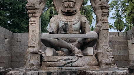 A huge stone statue kept on a pedestal with a cloudy sky in the background.