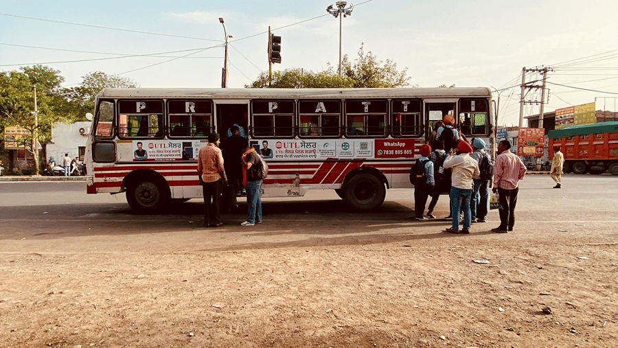 A red and white bus parked under a blue sky with people near its entrance
