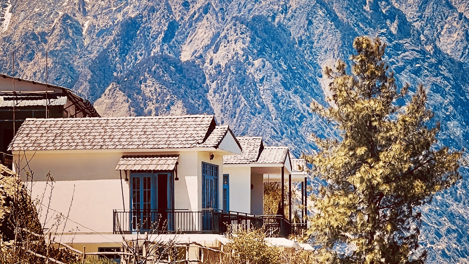 Cottage perched on a hillside with a towering mountain backdrop at Faraway Cottages, Auli.