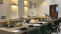 Seating arrangement at Aromas the best restaurant in Jamnagar at VITS, featuring cutlery and napkins placed on the dining table under warm lighting