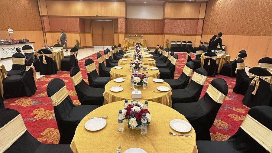  A view down a large, formal event hall set up with multiple round tables and chairs, each table set with dishes and a centerpiece.