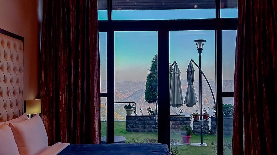 Cosy bedroom with a balcony and full-length windows offering valley views at Aranya Himalayan Retreat, Mashobra.