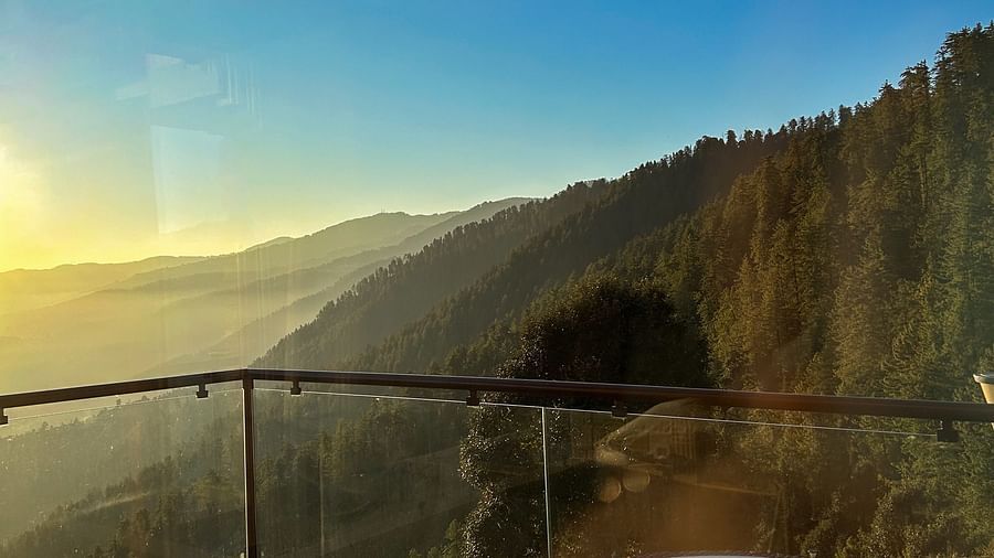 Balcony seating with table and chairs overlooking a golden sunrise and forested hills at Aranya Retreat, Mashobra.