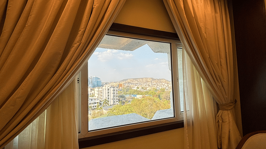 A view of the layered window curtains and a portion of a side table in the Superior Twin room at Clarks Amer, Jaipur.