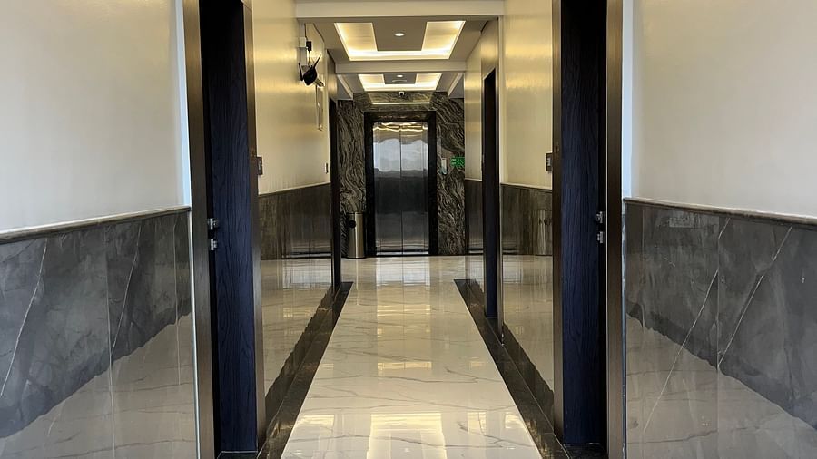 Another angle of a hotel corridor lit by bright lights with doors opening to the hotel rooms at VITS Select Kharadi, Pune.
