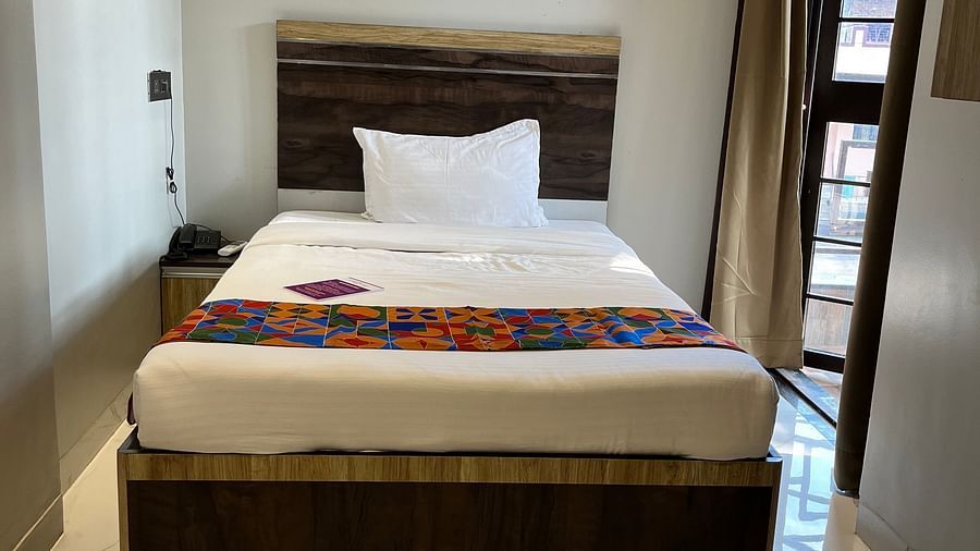 A front view of a bed in our room with a balcony door to the right at VITS Select Kharadi, Pune.