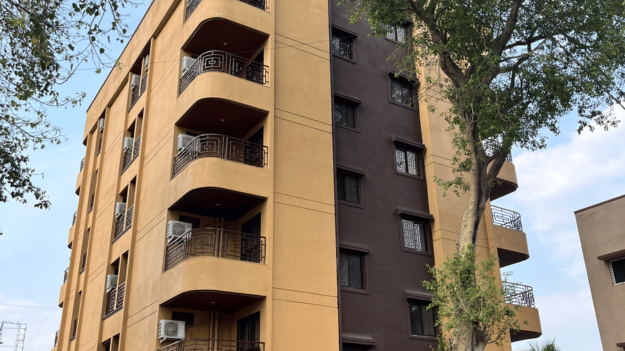 A multi-storey hotel building with curved balconies stands beside tall trees at VITS Select Kharadi, Pune.