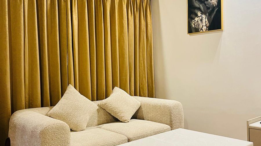 Lounge area of an Andaman Exotica room with a white sofa, coffee table, and dark wood trim.