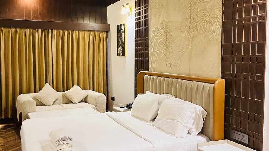 Bedroom area of an Andaman Exotica room with a large bed, decorative wooden headboard, and wood-paneled walls.