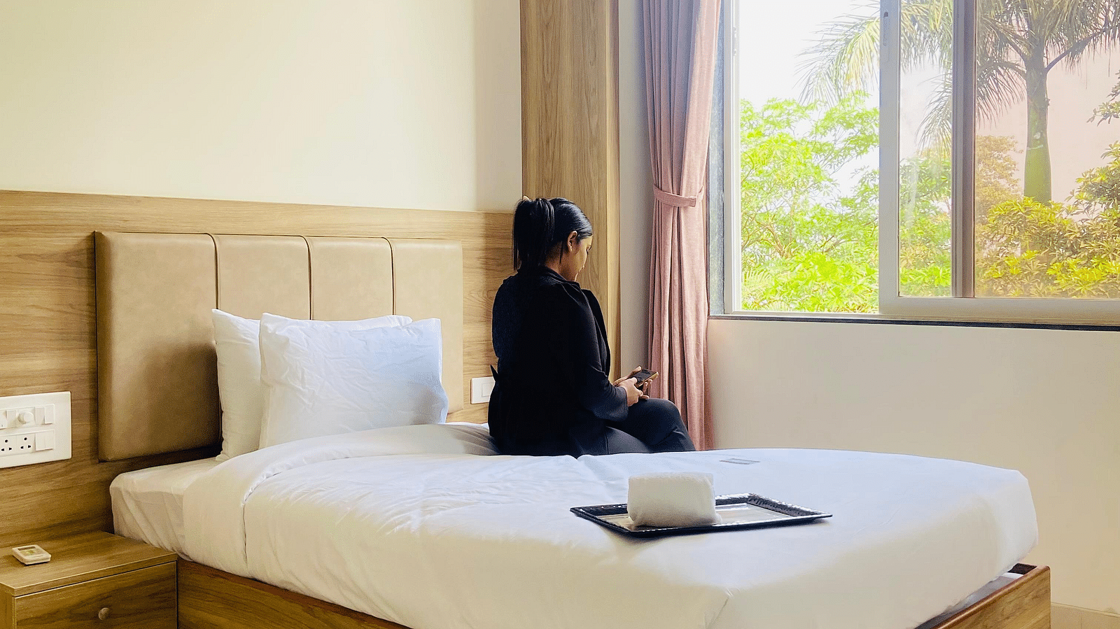A similar hotel room setup to the first, showing the same elements like the bed, lighting, and furniture.