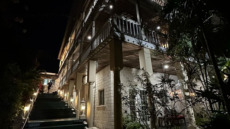 A dimly lit facade of a building with stair lights amidst trees at night | A Stone's Throw Away