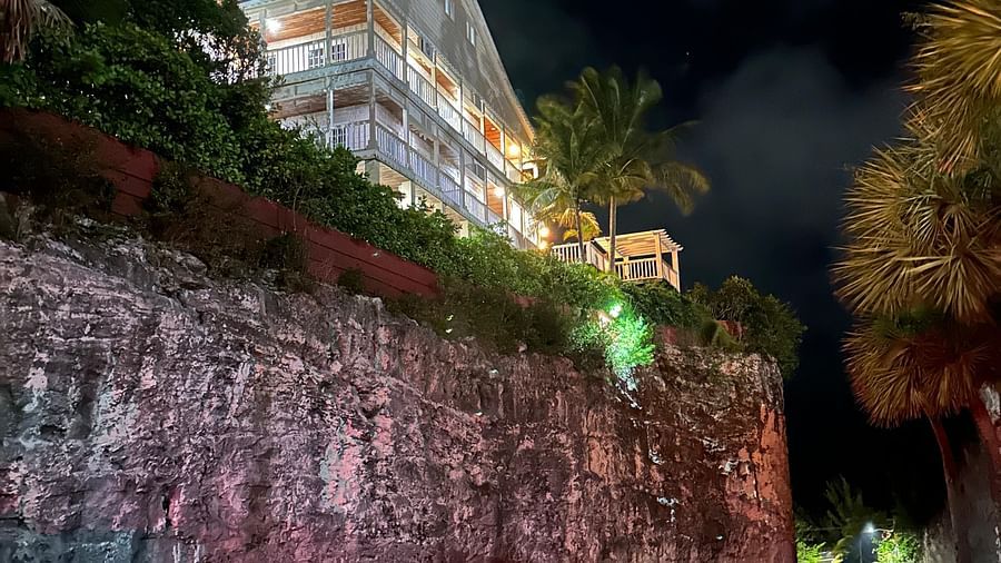 A road lit by headlights at night with a building on a hill in the background | A Stone's Throw Away