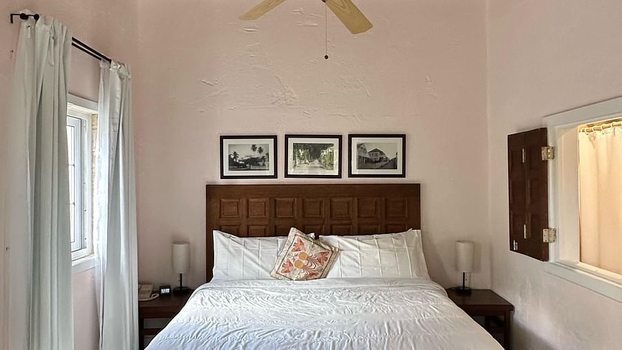 A bedroom with a bed covered in white linens and dark wooden floors | A Stone's Throw Away