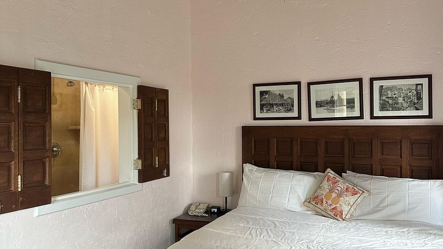 Bedroom with a bed covered in white linens and has a wooden table in front | A Stone's Throw Away