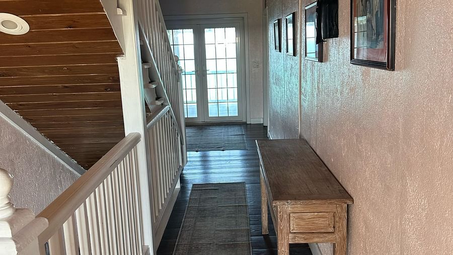 Indoor hallway with staircase and white railing | A Stone's Throw Away