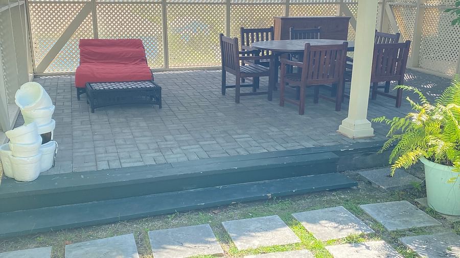 Patio with red lounger, dining table, and thatched roof, stone flooring in foreground | A Stone's Throw Away