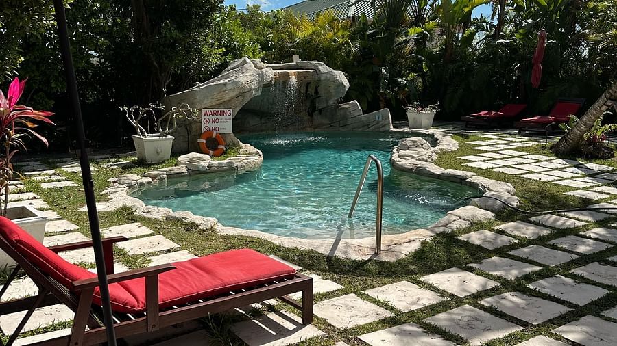 Poolside lounge chairs with red cushions and umbrella | A Stone's Throw Away