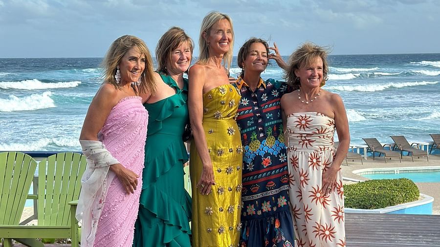Four women posing on a deck near the beach side. 