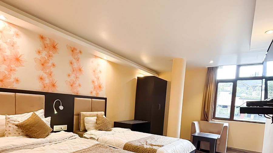 A bedroom with two queen beds and a floral wallpaper behind the beds at Avianna Hungry Jack, Gangtok.