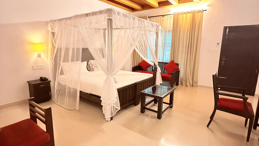 An overview of a bedroom inside the villa with a four posted bed, chairs and a ceiling fan in view at Ayur On The Beach Nattika.