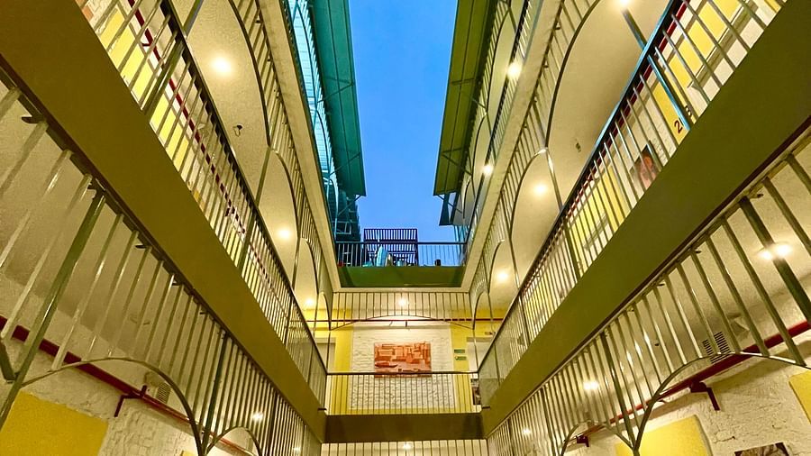 An image of the corridor at Bedzzz Varanasi, brightly lit, with a few wall paintings hanging on the walls, covering three floors in the picture.