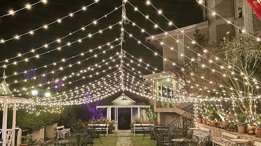 Evening wedding event at Cedar Inn, Darjeeling, showing festoon lights over the garden walkway and decorated seating area.