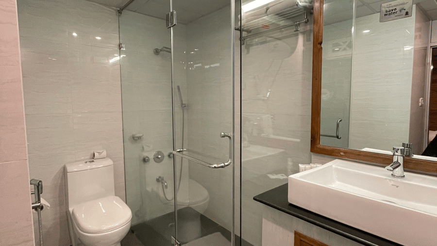 Modern bathroom with frameless glass shower, toilet, and wooden vanity with countertop, tiled walls at Cedar Inn.