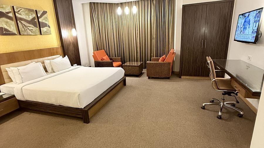 A spacious room with a large bed, cushioned seating beside the window with curtains, and a TV with a writing desk to the side | Cenneys Gateway