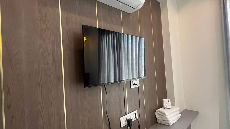 Wall-mounted TV right below the wall-mounted AC in the Daksh Bliss room at Daksh The Valley Resort, Saputara.