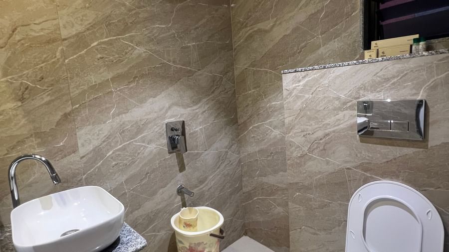 Bathroom of Daksh Comfort Room furnished with a western commode, a sink, and other bathroom fittings | Daksh The Valley Resort, Saputara