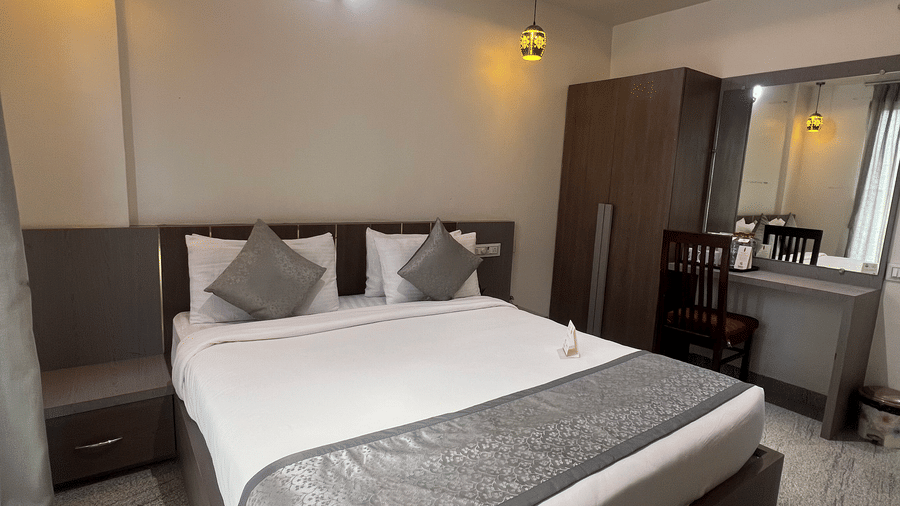 Queen size bed, wardrobe, as seen from the foot of the bed, in the Superior Room with Mountain View at Daksh The Valley Resort, Saputara.