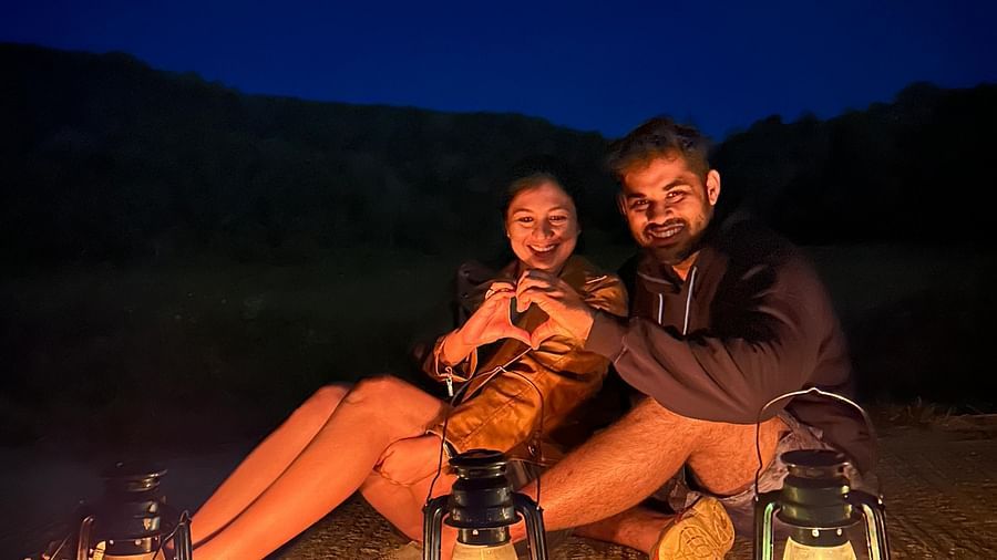 A couple posing for the camera with three lanterns in front of them and a dark blue sky in the background - Evergreen County