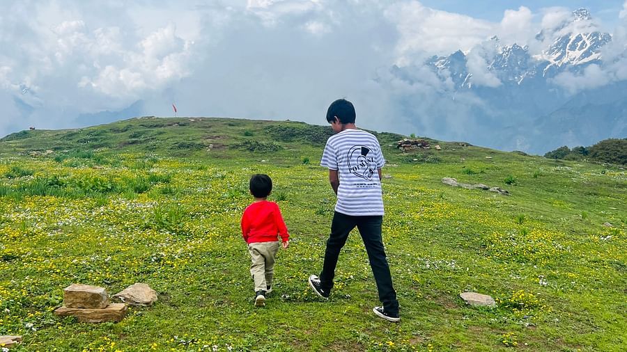 Image of two individuals walking on a green meadow at Garson Meadow | Faraway Cottages, Auli