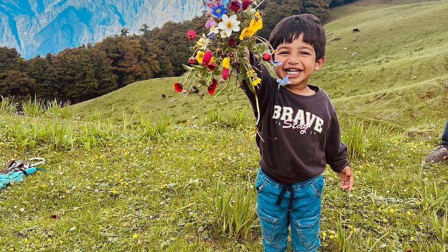 Image of a child holding up a bunch of flowers at Garson Meadow | Faraway Cottages, Auli