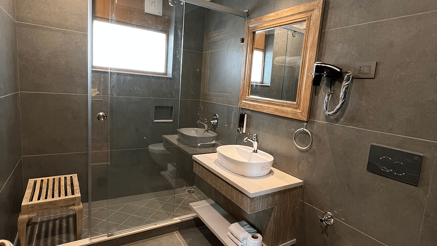 A cozy bathroom at Fishermen's Lodge, Bhimtal, featuring warm wooden furnishings and a stylish wall-hanging mirror, creating a relaxing atmosphere.