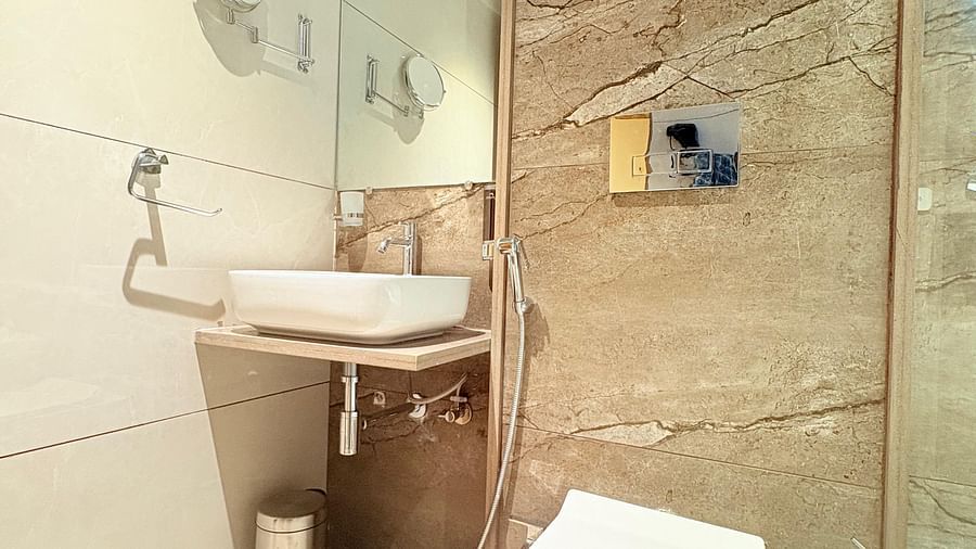Bathroom featuring a wash basin, a mirror, and a toilet at Hotel Mumbai House, Vashi.