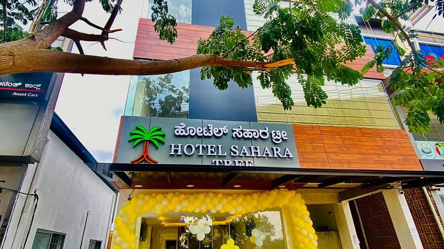 Welcoming entrance with bright yellow drapes and lush greenery at Hotel Sahara Tree.