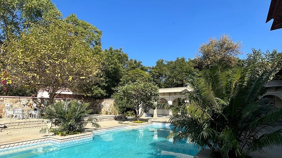An outdoor swimming pool surrounded by trees and heritage architecture - Khas Bagh, Jaipur.