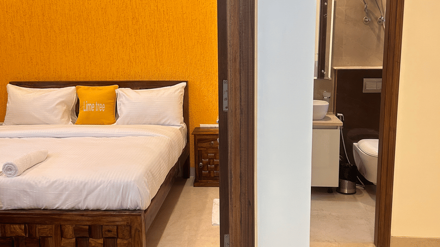 Suite of Lime Tree Hotels & Service Apartment Private Limited featuring an orange accent wall and a view into an adjoining bedroom.