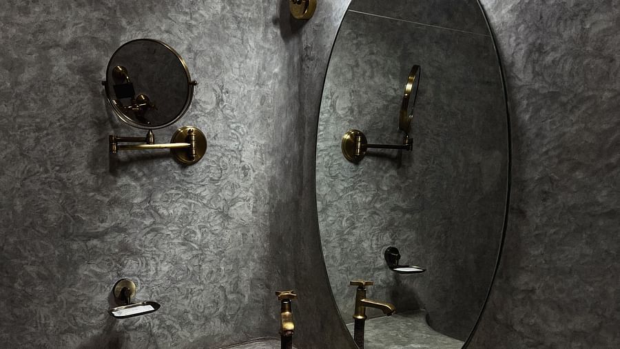 Yellowfin-9-washroom with a circular mirror in fornt a grey tiled washroom and a golden wash basin interior.