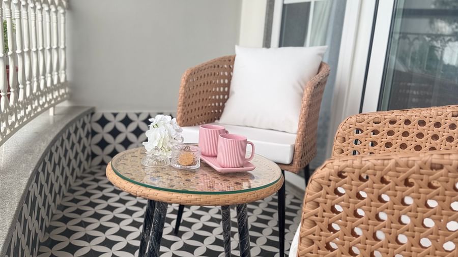 Outdoor balcony seating with rattan chairs and a tea set on patterned flooring - Mayfair Cafe & Suites, Dalhousie