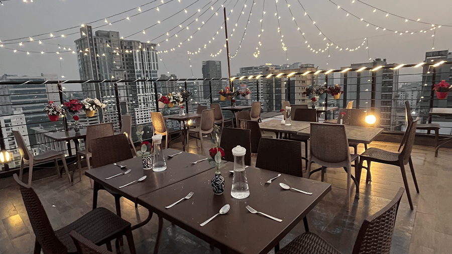Rooftop dining setup with cutlery and warm evening lighting.
