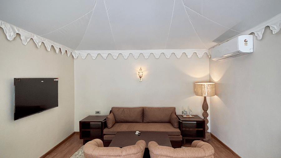 Living are of Vana Suite at Surpura Bagh featuring sofa sets, cabinet tables on either side, a centre table, a flat TV screen, and a lamp at one corner.