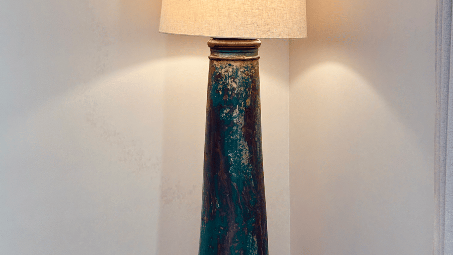 A corner of Vana Junior Suite featuring a tall lamp which is lit, making the corner illuminated.
