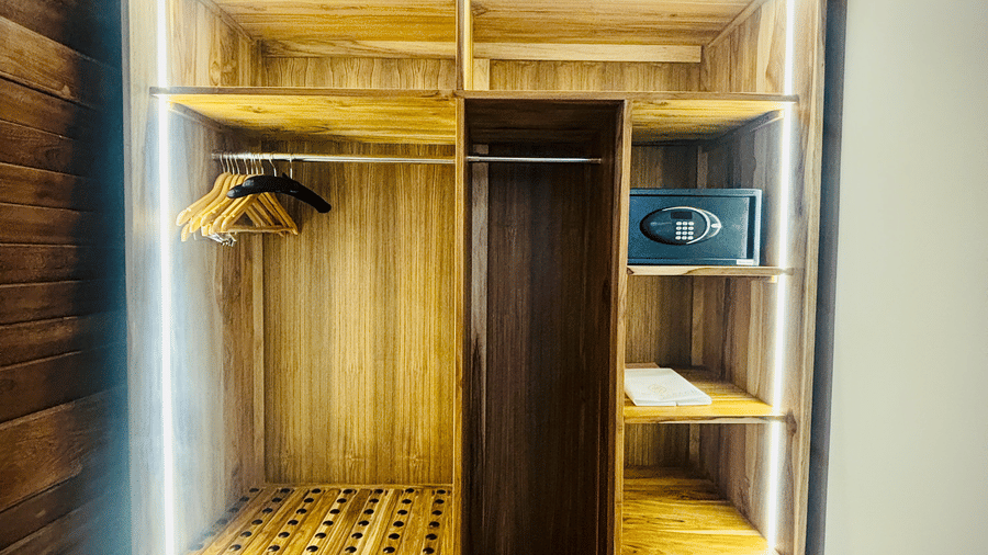 Walk-in wardrobe at Vana Junior Suite featuring lights fixtures on several sections, hangers in one corner, safety lockers, and other things at Surpura Bagh.