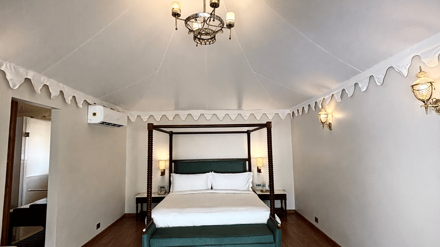 Bedroom of Vana Suite at Surpura Bagh featuring poster bed, chandelier light on top, lamps, bedside table, etc.