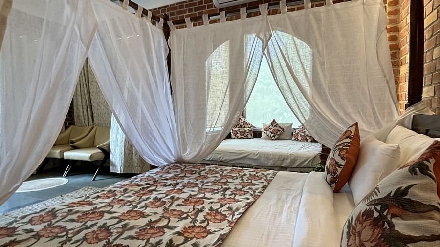 Four-poster canopy bed with floral bedding in a warmly lit room at Tisya Farms, Gurgaon