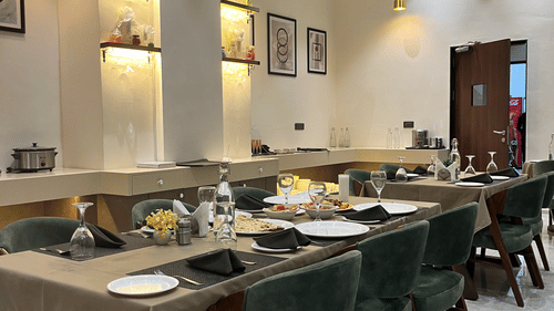 Seating arrangement at Aromas the best restaurant in Jamnagar at VITS, featuring cutlery and napkins placed on the dining table under warm lighting