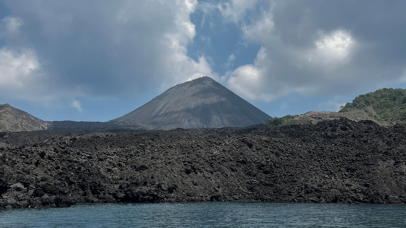 Barren Island volcanic formation rising from the sea under a cloudy sky photographed during a diving expedition with Barefoot Scuba Resort.