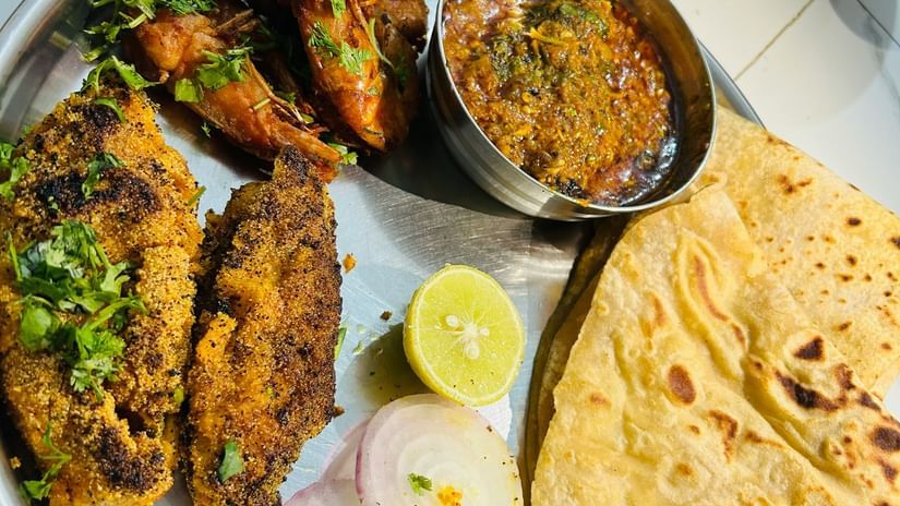 A simple, home-style Indian meal of roti (flatbread), sliced raw onion, lemon, and a portion of dry-cooked vegetable or meat curry served on a steel plate.